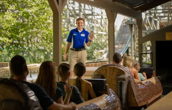 A Team Member waves to riders as they depart the station at Frightful Falls.