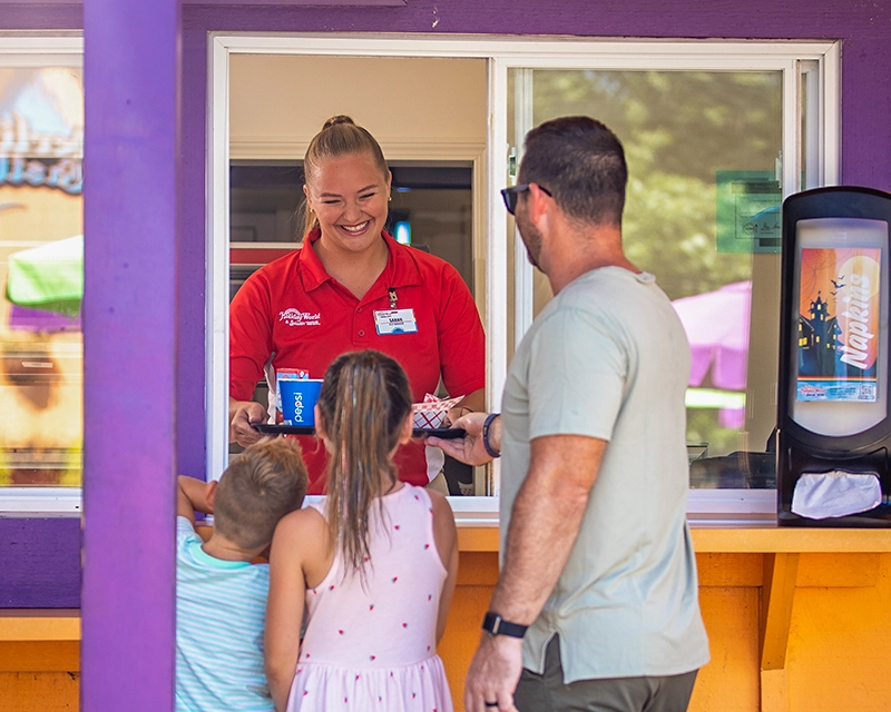 A Team Member hands a family their food through the window at Goblin Burgers.