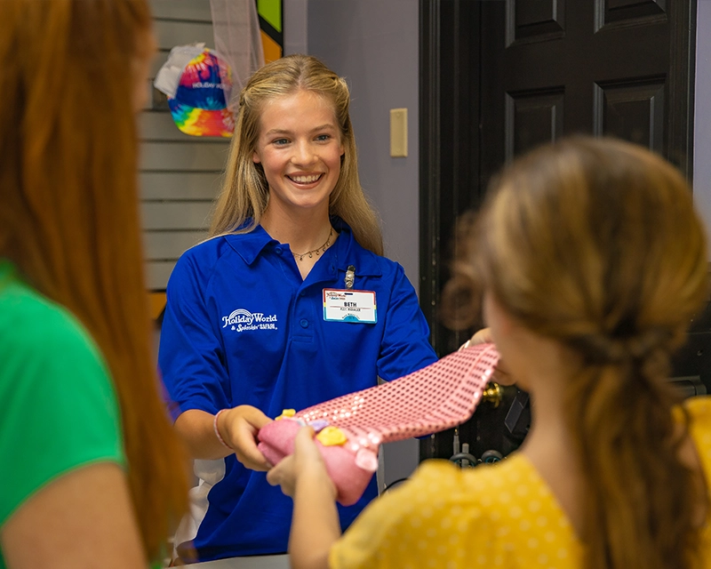 A Team Member assists a young girl and her mother at Spooky's Hat Shop.