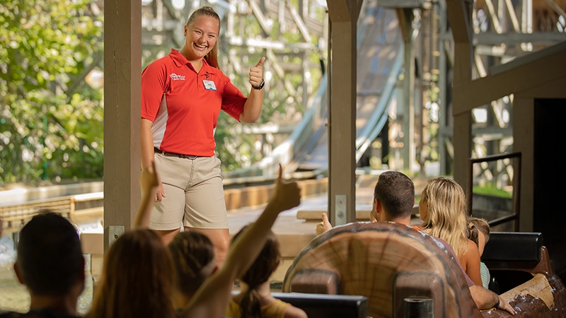 A Team Member trades thumbs-up with Guests riding Frightful Falls.