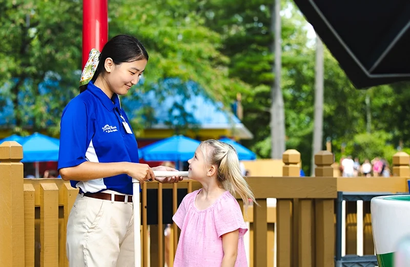 A Team Member measures a young girl's height at Kitty's Tea Party.